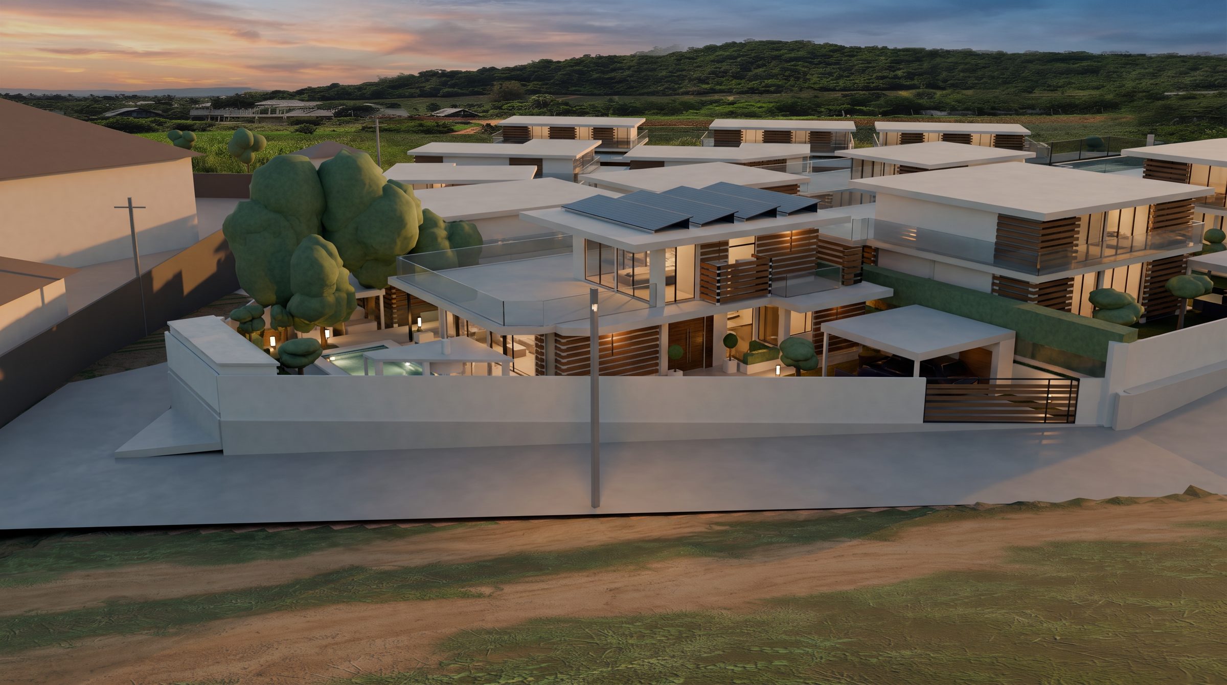 Rubicon Estate at dusk, seen from the road: white villas with teak screens on their terraces, green fields and hills beyond
